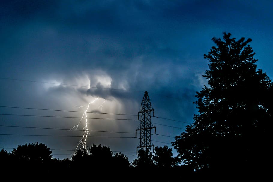 silhouette photo of trees near electric tower under lightning, fork lightning struck on trees