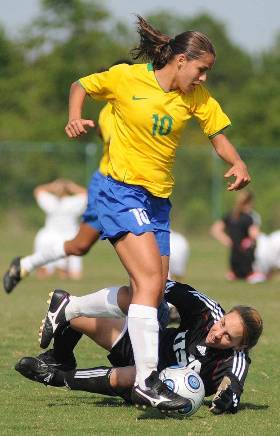 selective focus photo of woman in black laying on ground while catching ball beside woman in yellow shirt