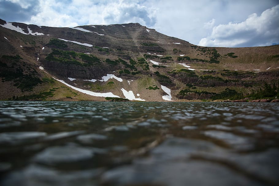 low angle photography of body of water and mountain, low-angle photo of gray and brown mountains HD wallpaper