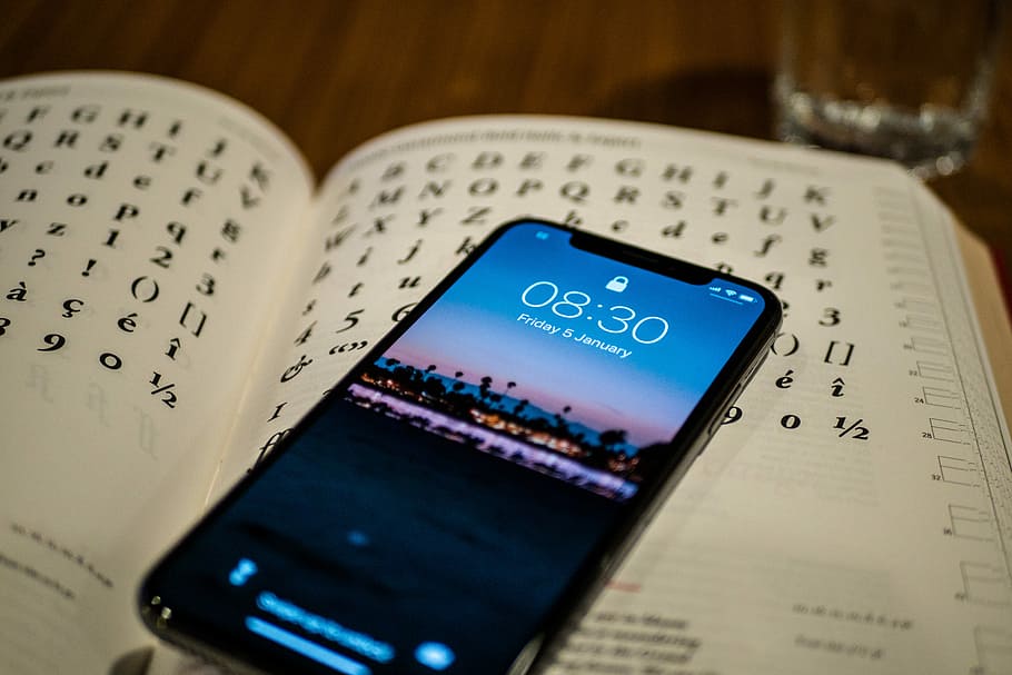 black Android smartphone on book, silver iPhone X on opened book HD wallpaper