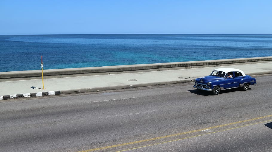 classic blue vehicle passing beside body of water during daytime HD wallpaper