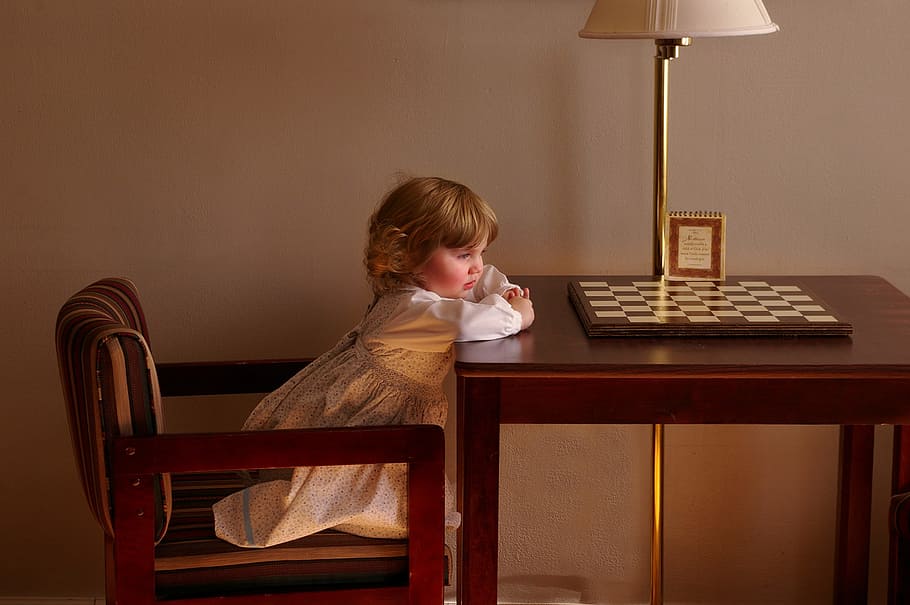 Child Setting on Chair in Front of Table, chess board, desk, furnitures