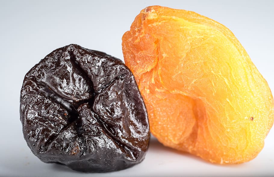two orange and black dried fruits, dried apricots, prunes, yellow