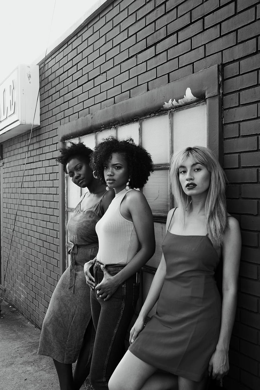 greyscale photo of three women leaning on wall, grayscale photo of three standing woman with brick wall behind them, HD wallpaper