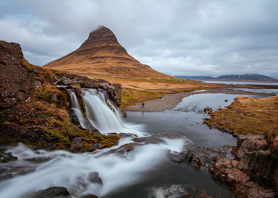 mountain near body of water under blue sky during daytime, brown mountain with river flowing HD wallpaper