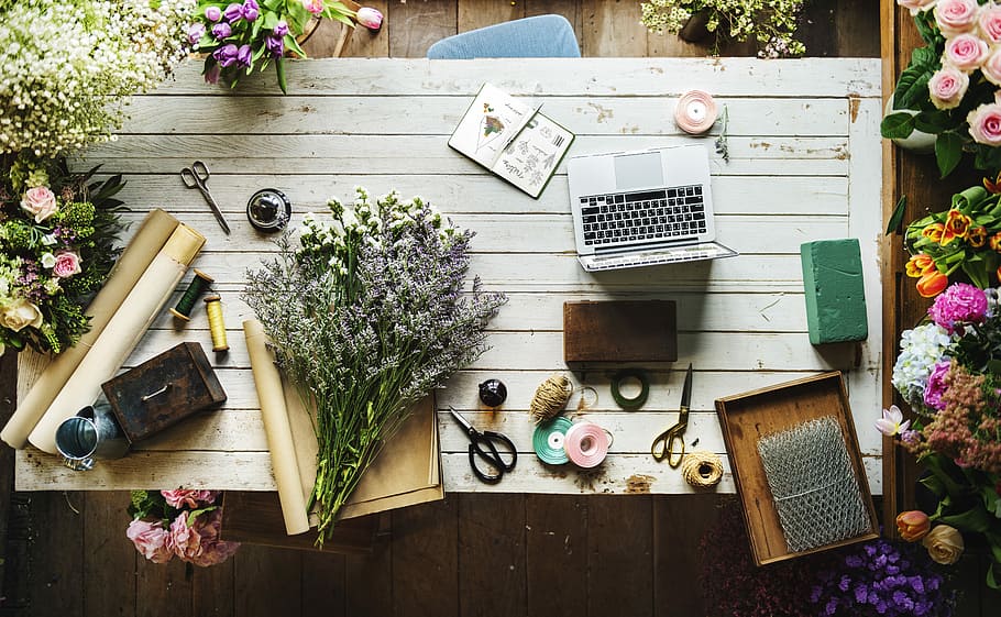 Table at the florist’s, flowers on brown paper and near laptop HD wallpaper