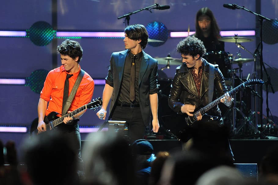 four men band performing on stage, jonas brother, entertainers