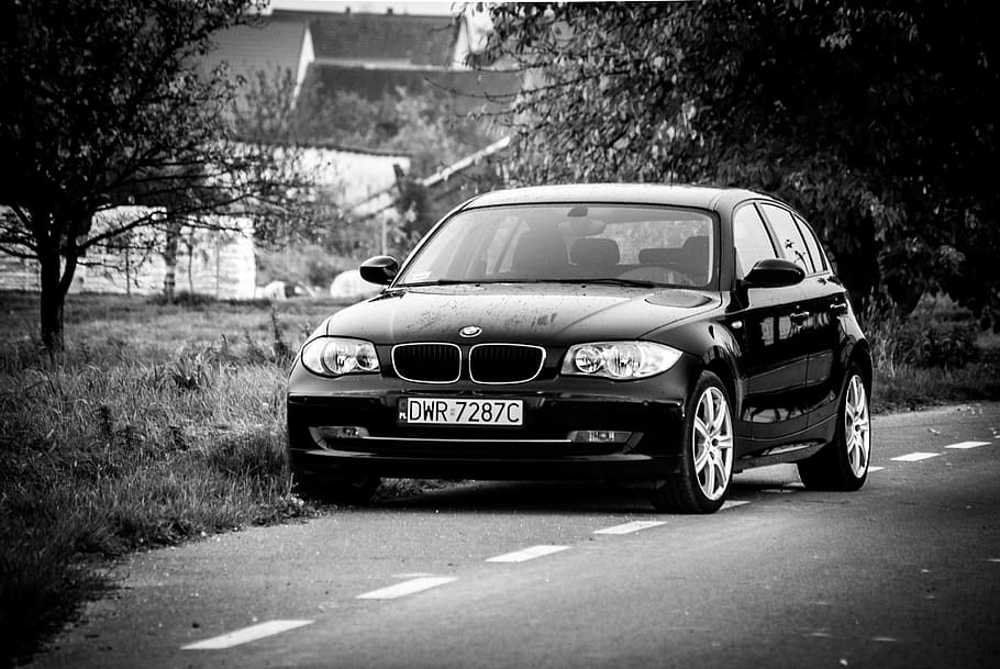 BMW 1-series 5-door hatchback on road near trees and houses at daytime
