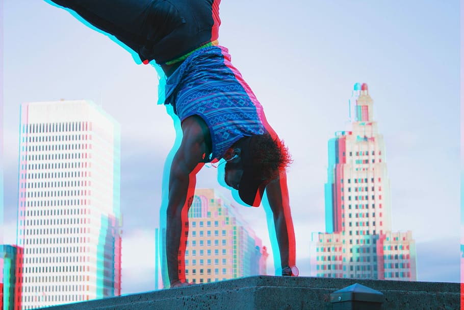 man at the top of the building making cartwheel, man hand stand on concrete with high rise building in distance, HD wallpaper