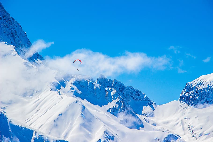 photo of person with parachute above snowy mountain, person paragliding over snow covered mountain HD wallpaper