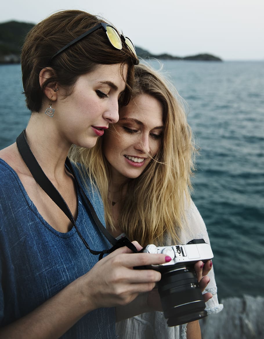 woman holding DSLR camera beside woman looking on camera, casual