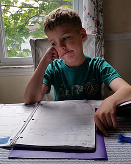 boy wearing green shirt sitting in front of table and spiral notebook HD wallpaper