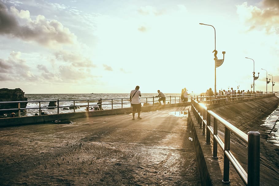 Man Wearing White Shirt Walking on Concrete Pavement Near Sea HD wallpaper