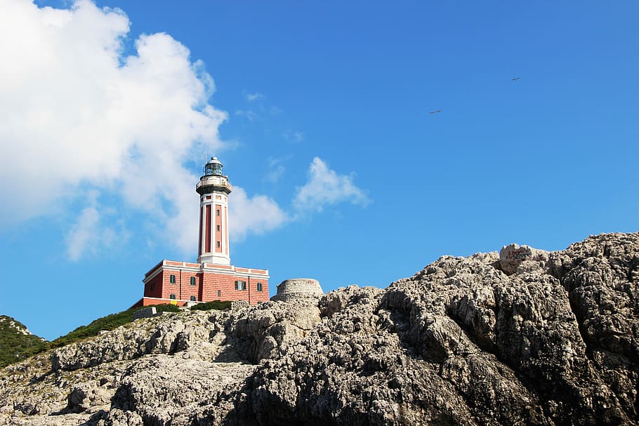 brown and white concrete lighthouse on rock formation during daytime, brown and white lighthouse on brown cliff during daytime HD wallpaper