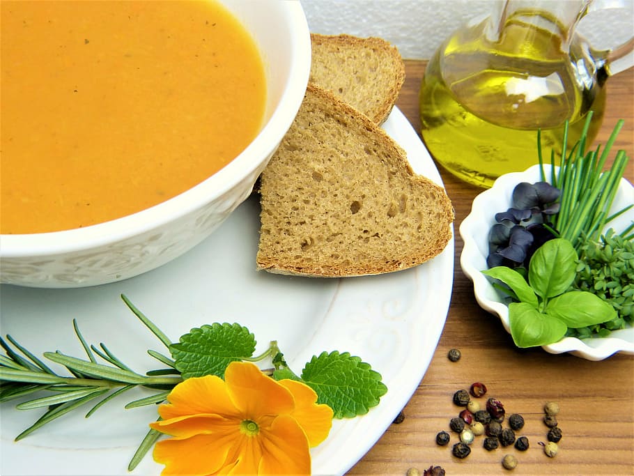 wheat bread beside oil, carrot soup, herbs, vegetables, lunch