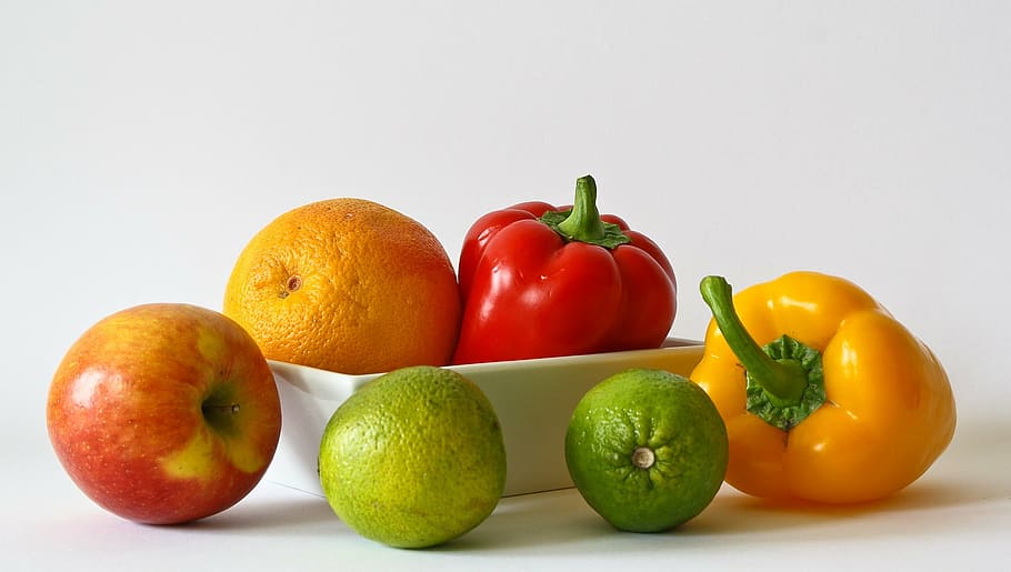 two bell peppers and four fruits on white surface, vitamins, orange