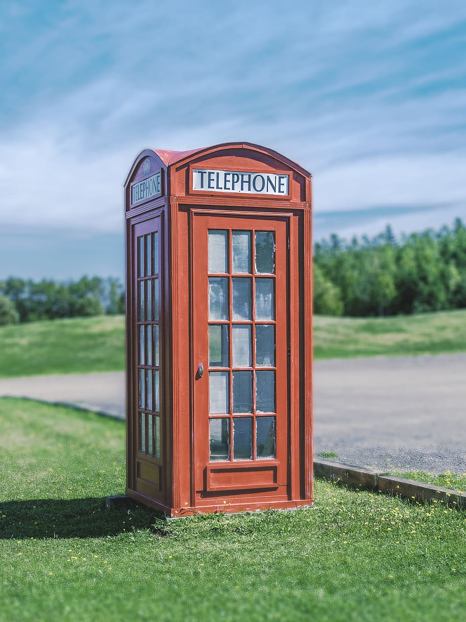 Telephone booth near road, brown telephone booth in the green field