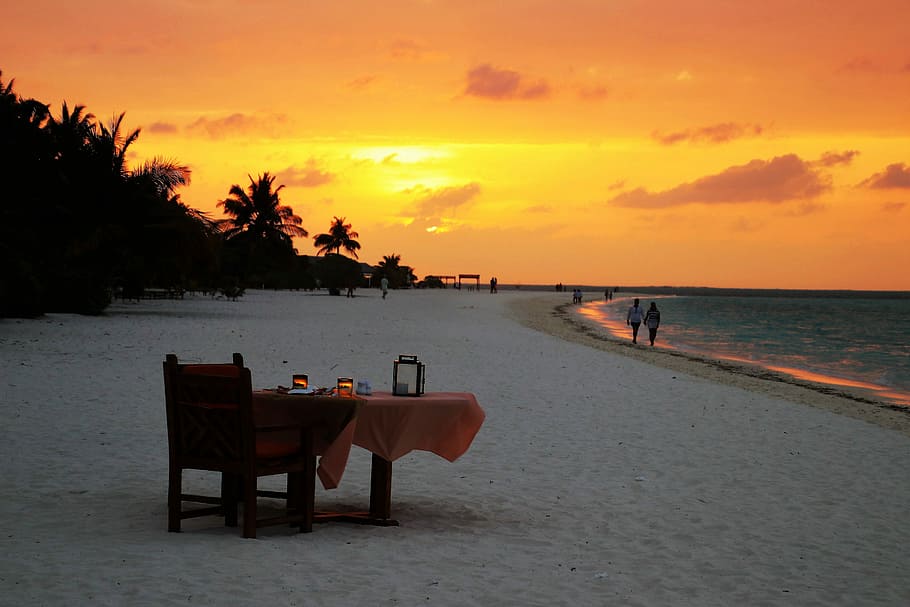 brown wooden armchair with table on seashore during golden hour HD wallpaper