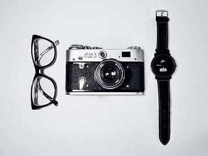 gray and black MILC camera beside watch and eyeglasses on white background HD wallpaper