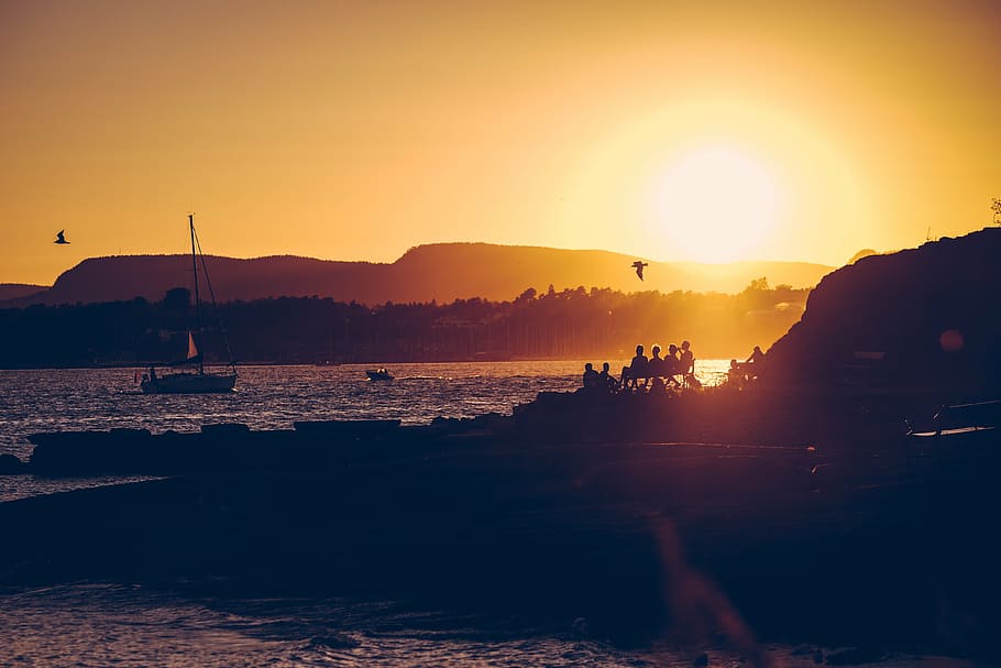 silhouette photography of people sitting on bench looking at beach HD wallpaper