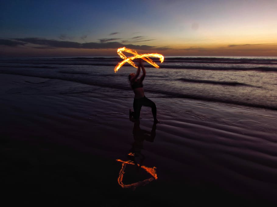 person doing fire dancing on seashore, woman fire dancing at seashore during golden hour HD wallpaper