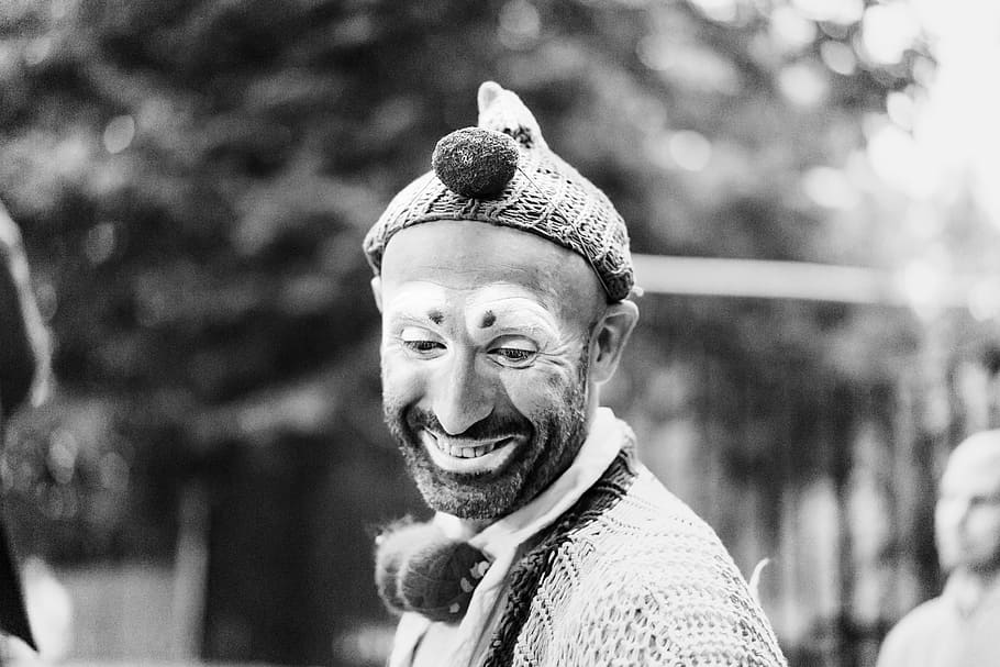 grayscale and depth of field photography of clown, man wearing knitted hat