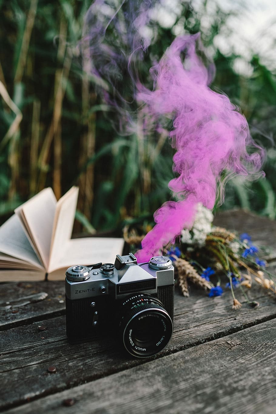 Colorful smoke bomb, book and vintage camera, wooden desk, wooden pier