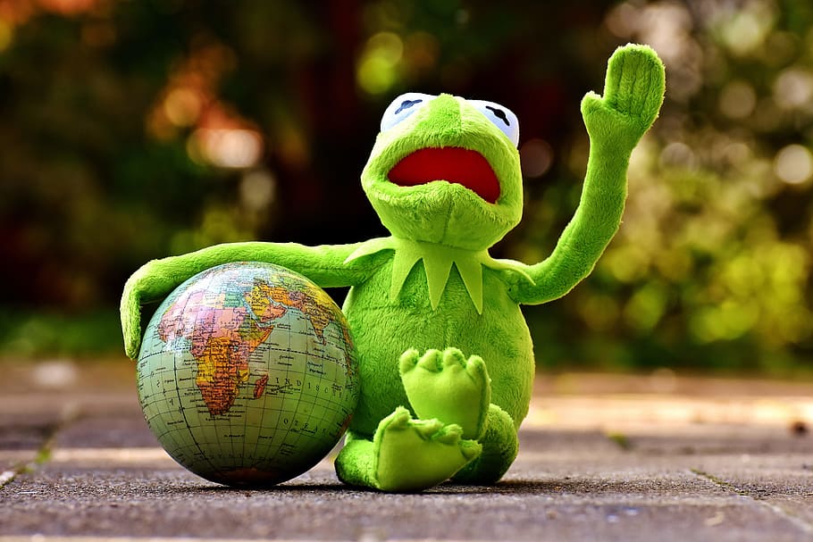 Kermit the frog with deskglobe on concrete ground, holiday greetings