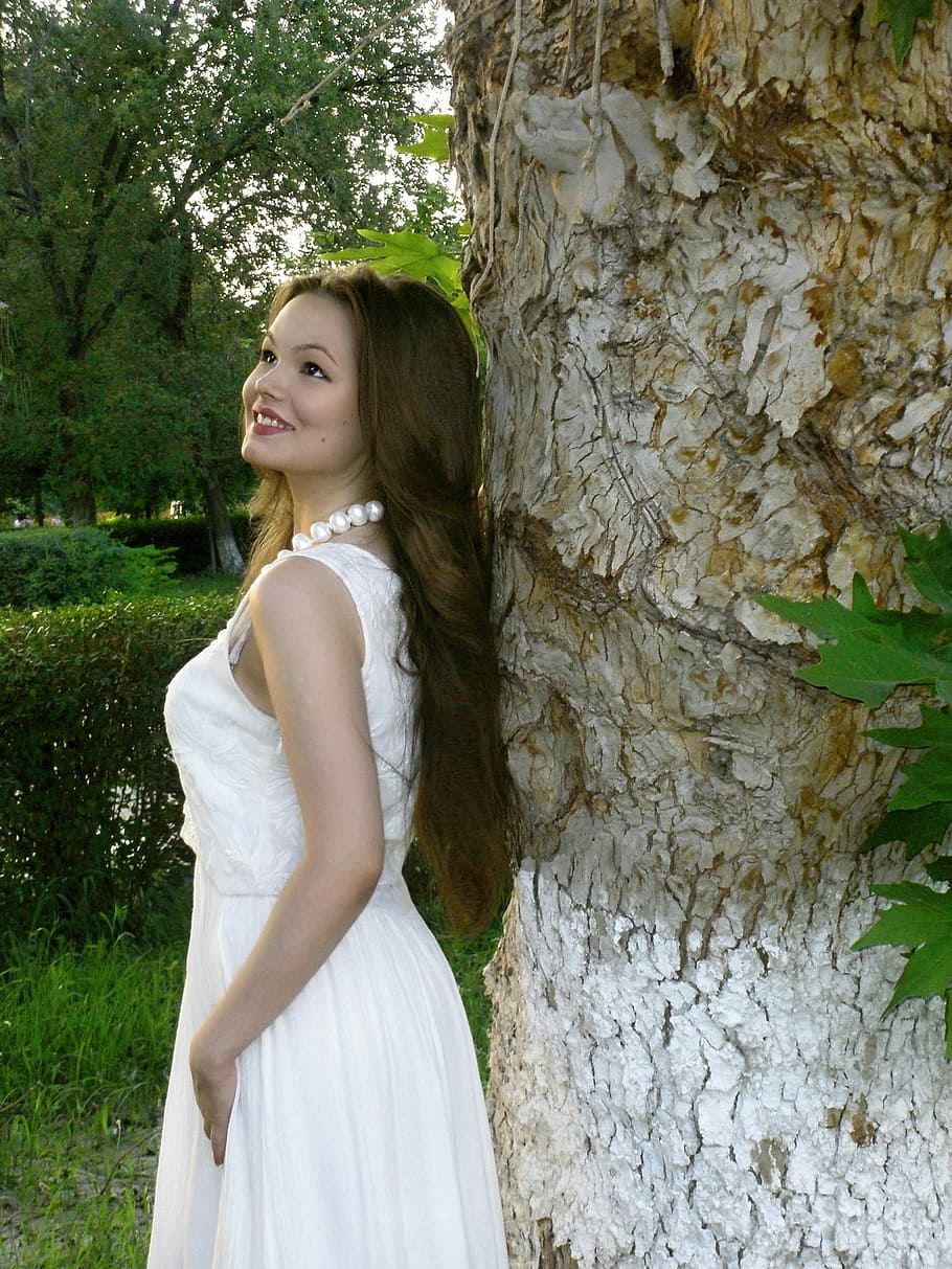 woman in white sleeveless dress looking up beside brown tree trunk, HD wallpaper