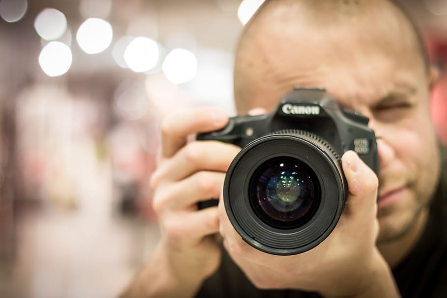 shallow focus photography of man holding DSLR camera, photographer