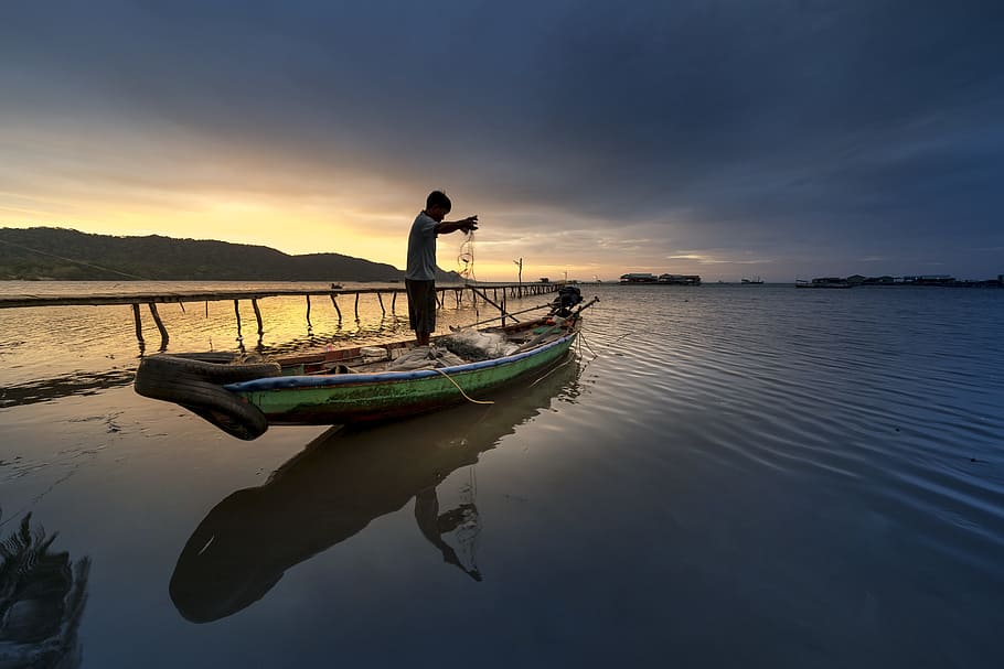photo of man standing on canoe and holding fish net, island, vietnam
