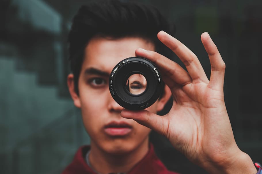 selective focus photography of man wearing red top, man peeking on camera lens HD wallpaper