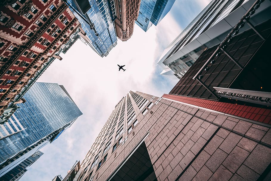 worm's-eye view of an airplane flying above city, airplane on the sky during daytime HD wallpaper