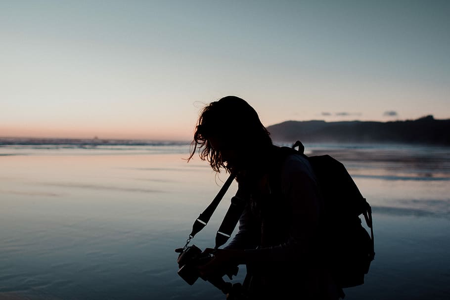 silhouette photo of man holding a camera beside body of water, silhouette of man playing guitar on shoreline during golden hour HD wallpaper