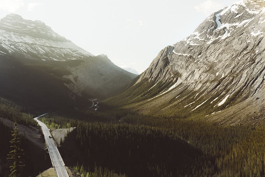 aerial photo of gray alphated road near mountain, aerial view cement road surrounded by forest during daytime HD wallpaper