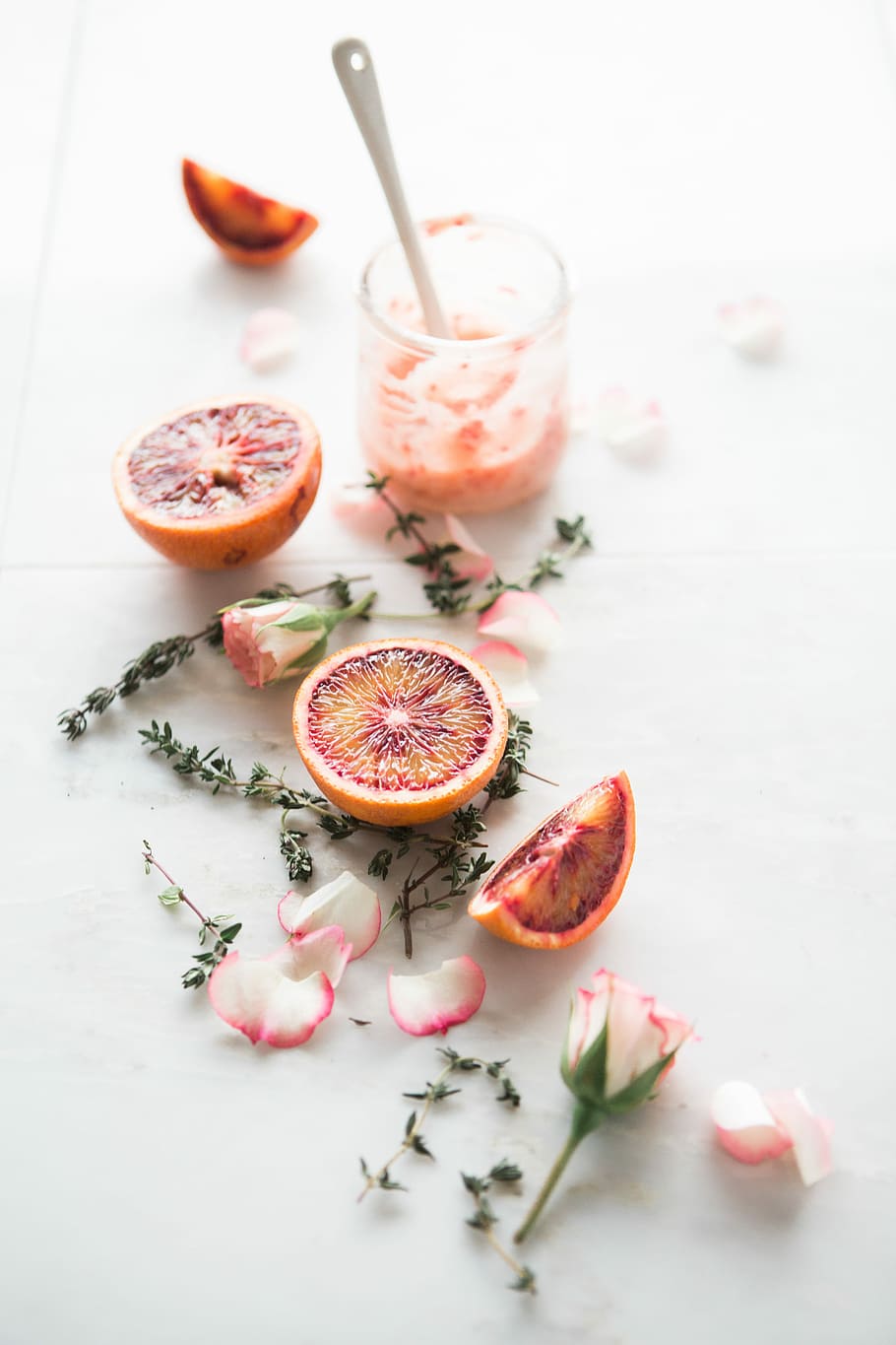 sliced blood orange fruits with white-and-pink petaled flowers beside, blood orange fruit near the glass HD wallpaper