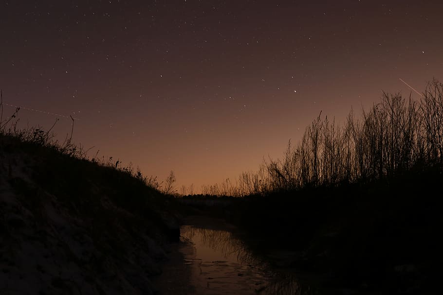 body of water in between grasses, silhouette of hill during night time HD wallpaper