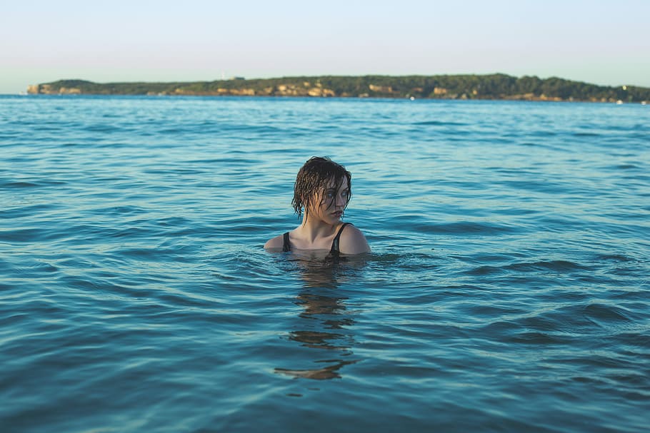 photography of woman in black swimming wear soaked in sea, woman on body of water during daytime
