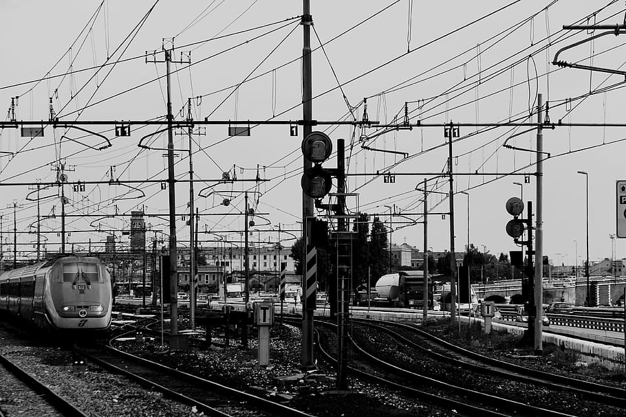 grayscale photo of black posts during cloudy season, grayscale photo of train on train rails at daytime