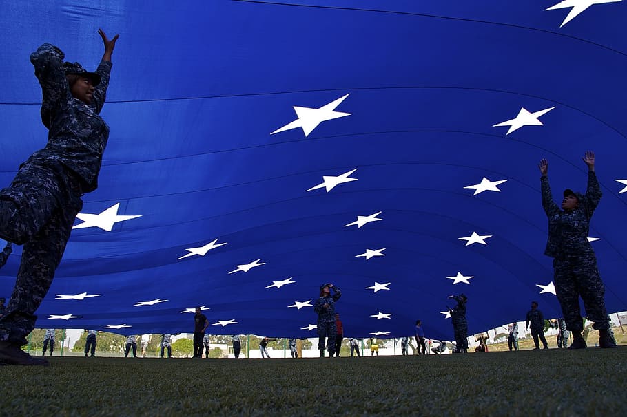 soldiers raising blue flag with white stars, giant flag, teamwork