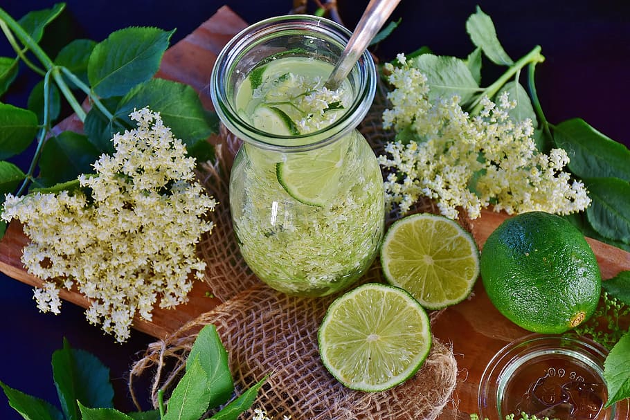 lemon juice in glass with spoon and lemon fruits, elder, flowers