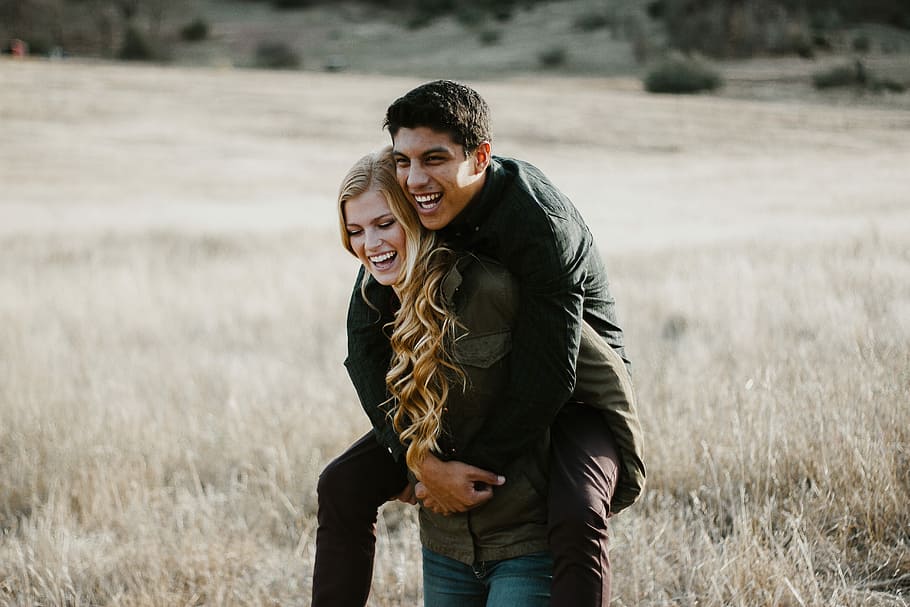 woman giving man piggyback ride, woman in green jacket carrying man HD wallpaper