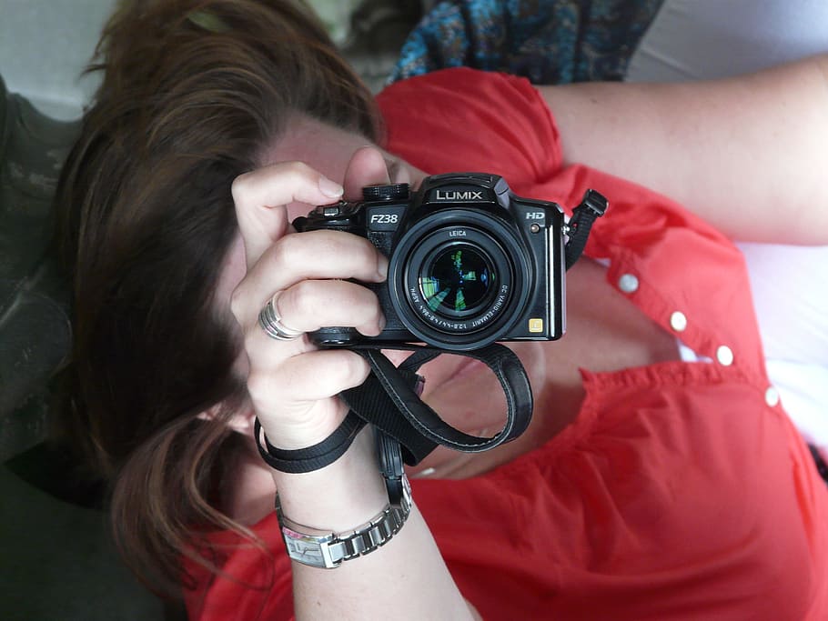 woman holding black Lumix DSLR camera, photographer, hand, attitude