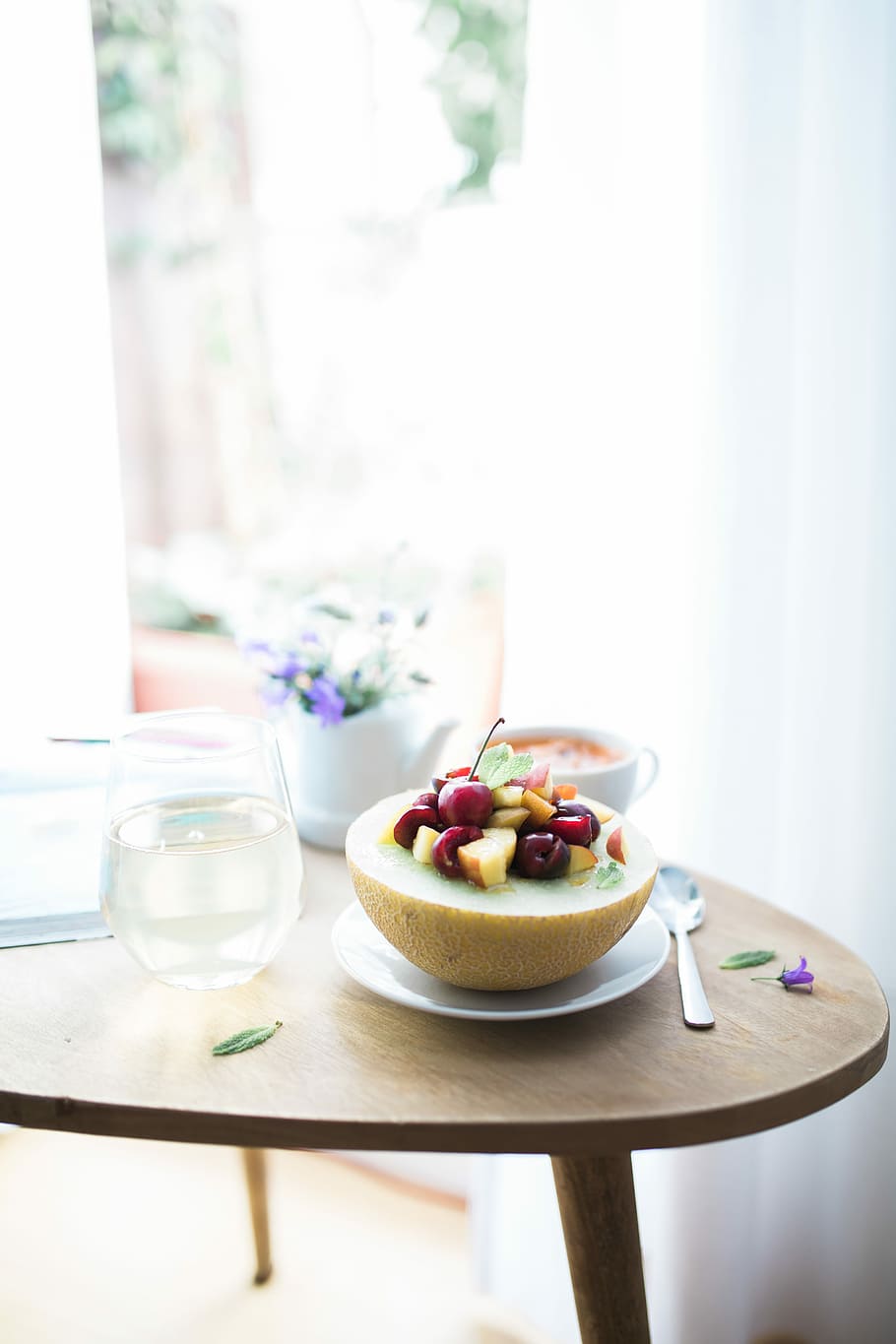 dessert dish filled white plate beside spoon, sliced fruit on white saucer besides footless wine glass on brown wooden table HD wallpaper
