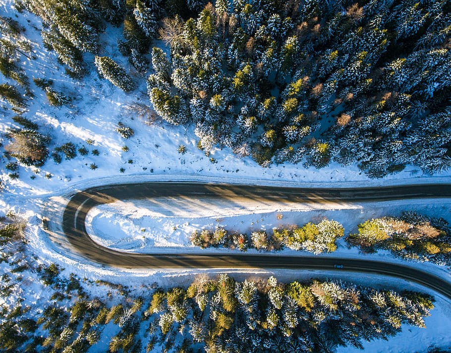aerial view of sharp curve road during daytime, white and green road and trees covered with snow HD wallpaper