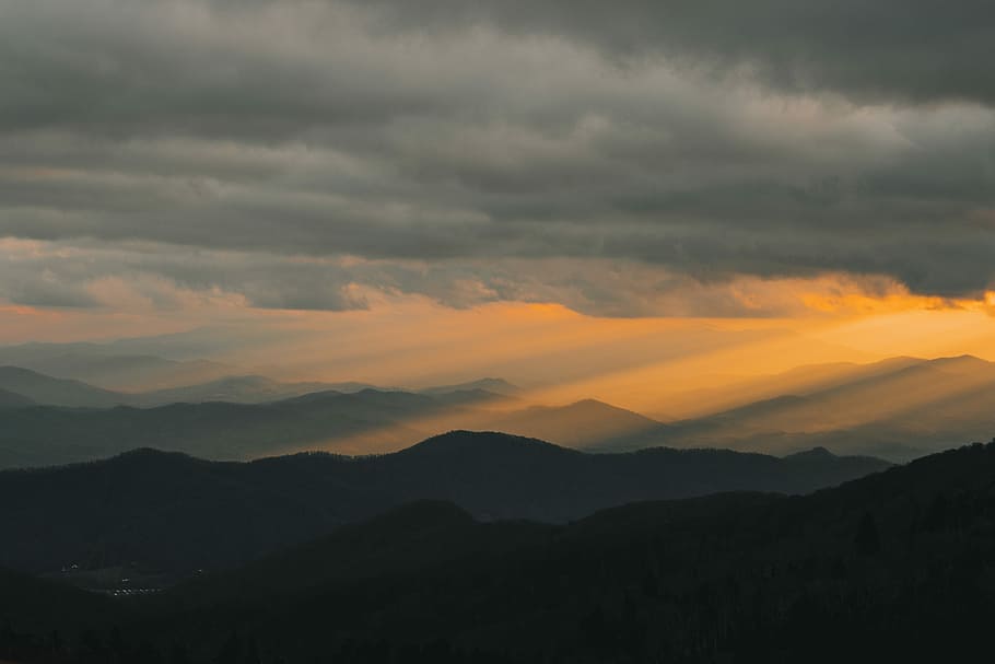 crepuscular rays shining over mountain ranges, mountain rage view under cloudy sky during daytime HD wallpaper