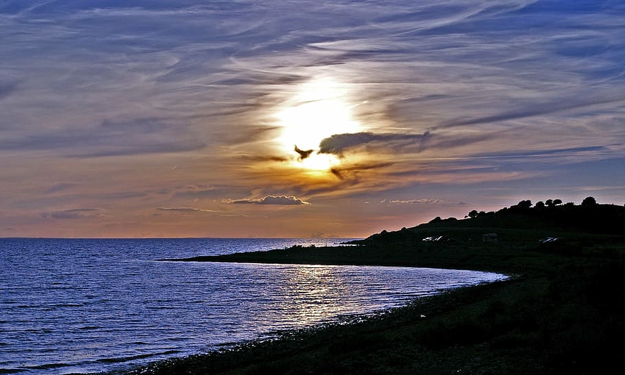 silhouette of island near shoreline during golden hour, sunset