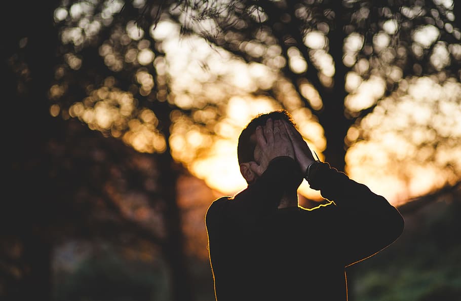 man wearing black long-sleeved shirt, man covering his face with his hands HD wallpaper