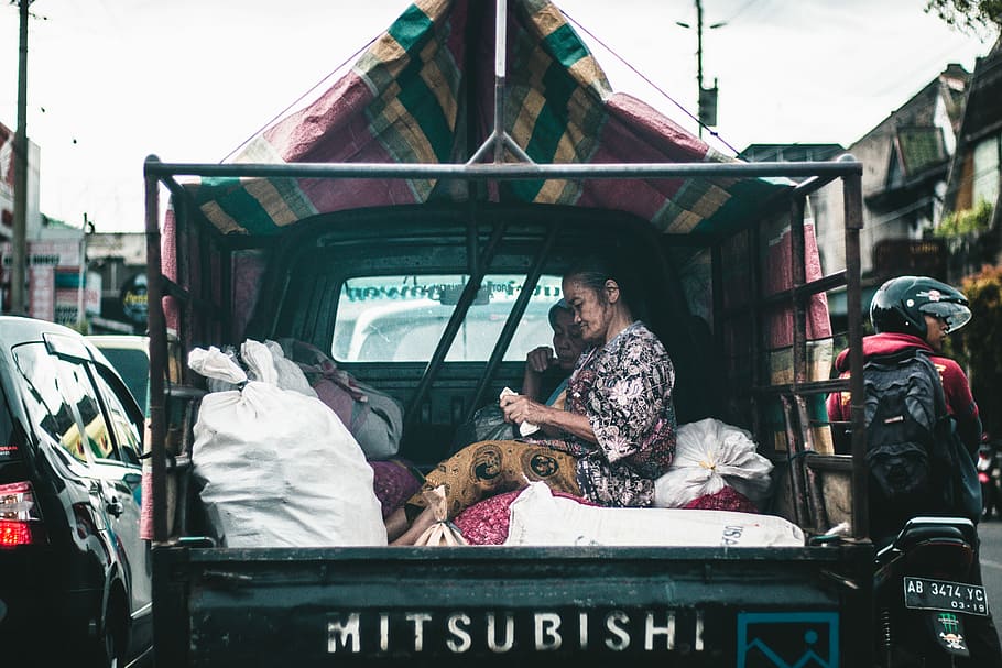 woman seating on drop side truck, woman sitting at the back of a truck