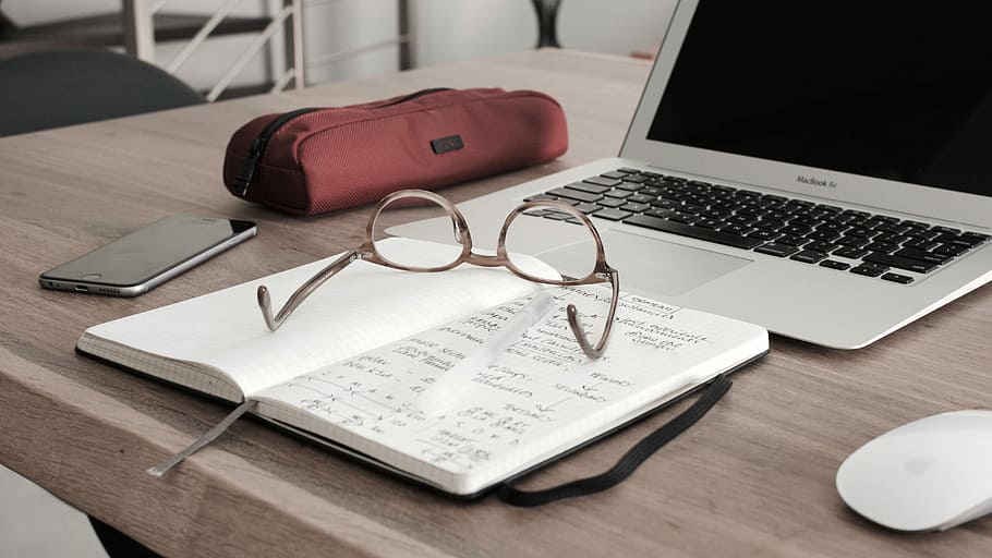 eyeglasses on book beside laptop, eyeglasses near MacBook Pro HD wallpaper